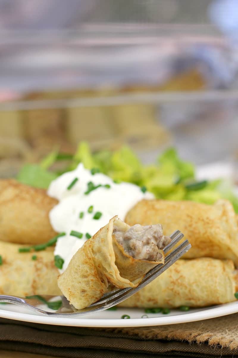 a fork holding a bite-sized piece of filled crepe