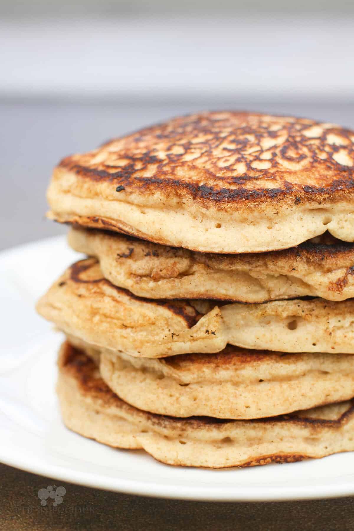 pancakes stacked on white plate, side view