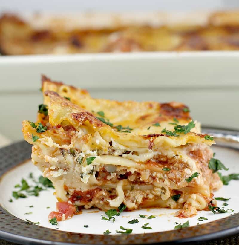 squared off side view showing the layers for the best lasagna ever with the rest of the casserole in the background