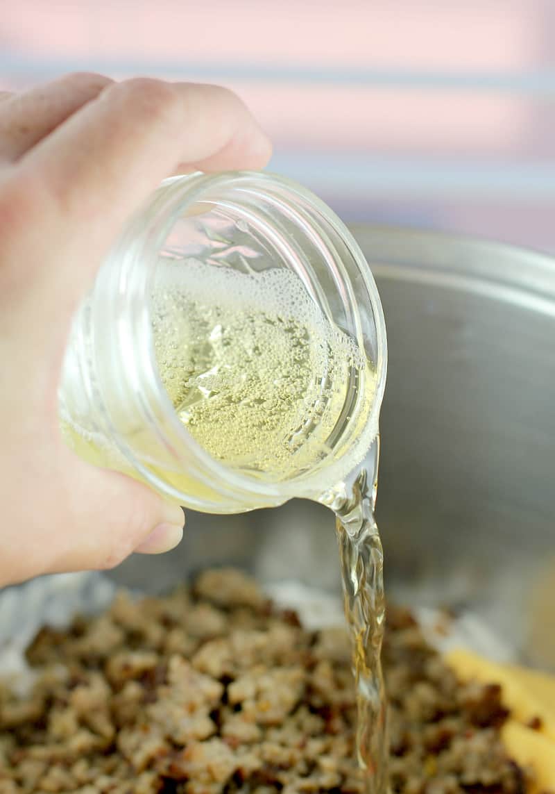 Small mason jar wiht beer being poured into the pot with the rest of the ingredients