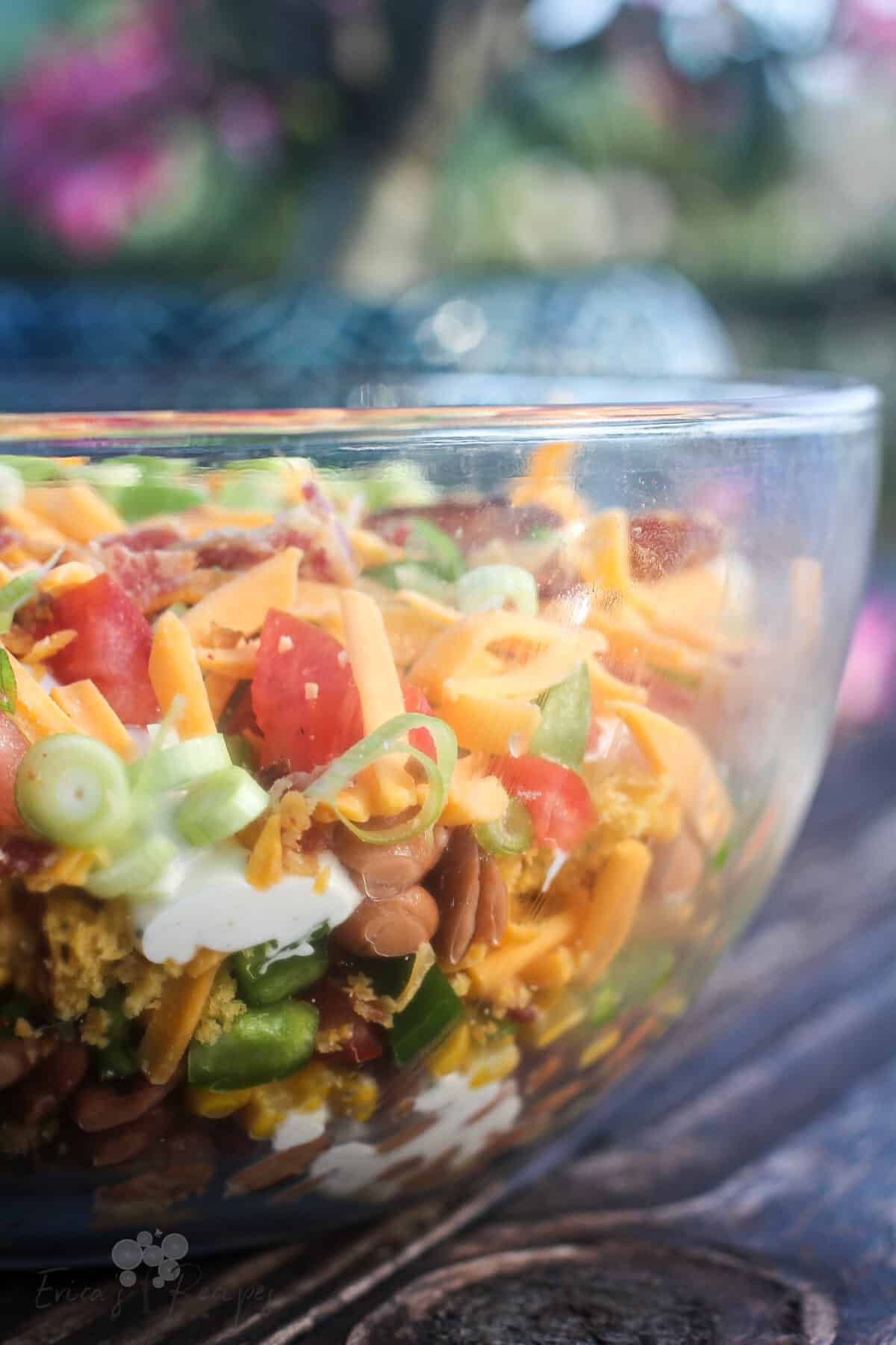 side view into glass bowl showing layers of cornbread salad