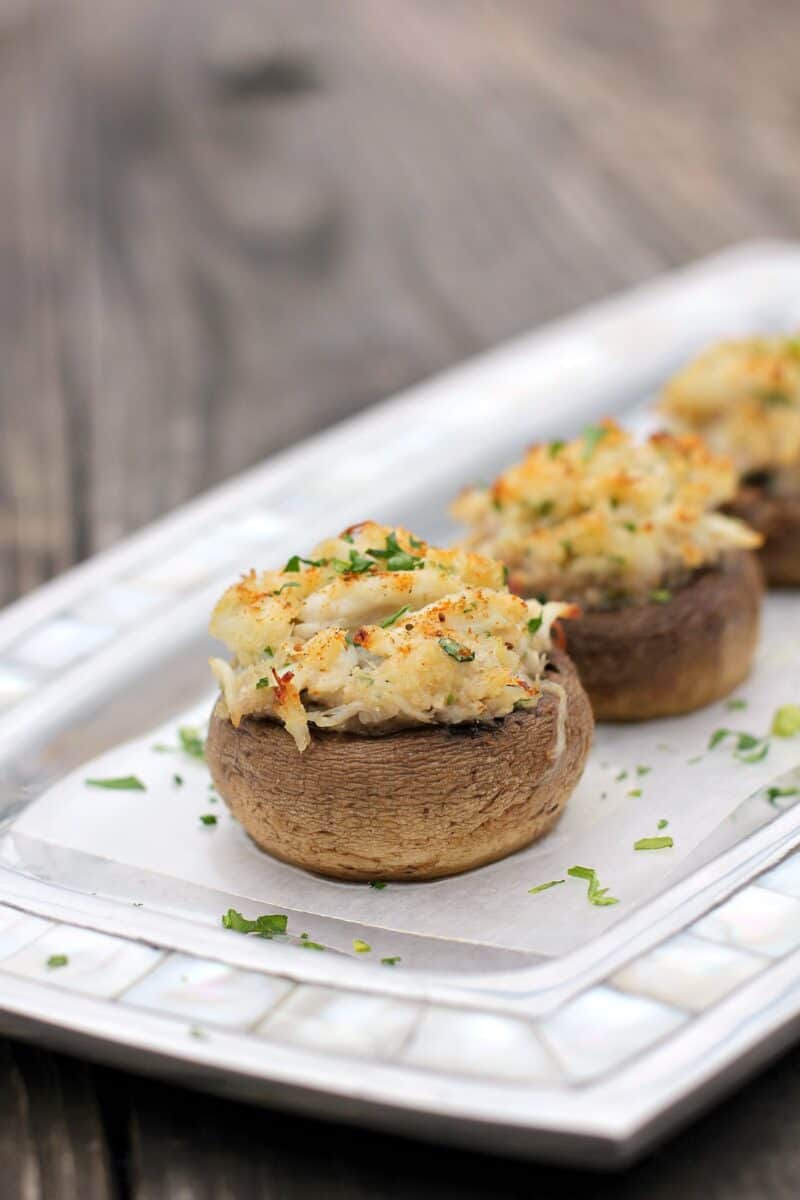 stuffed mushroom, centered, on serving plate topped with sprinkling of parsley