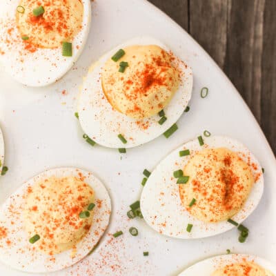 top down view of deviled eggs topped with chives on a white serving platter