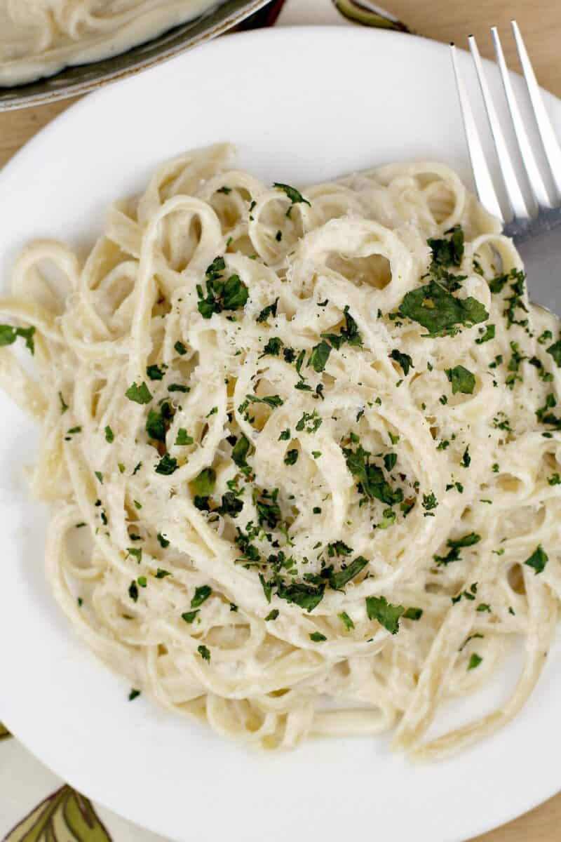 top down view of pasta on a white plate, topped with herbs