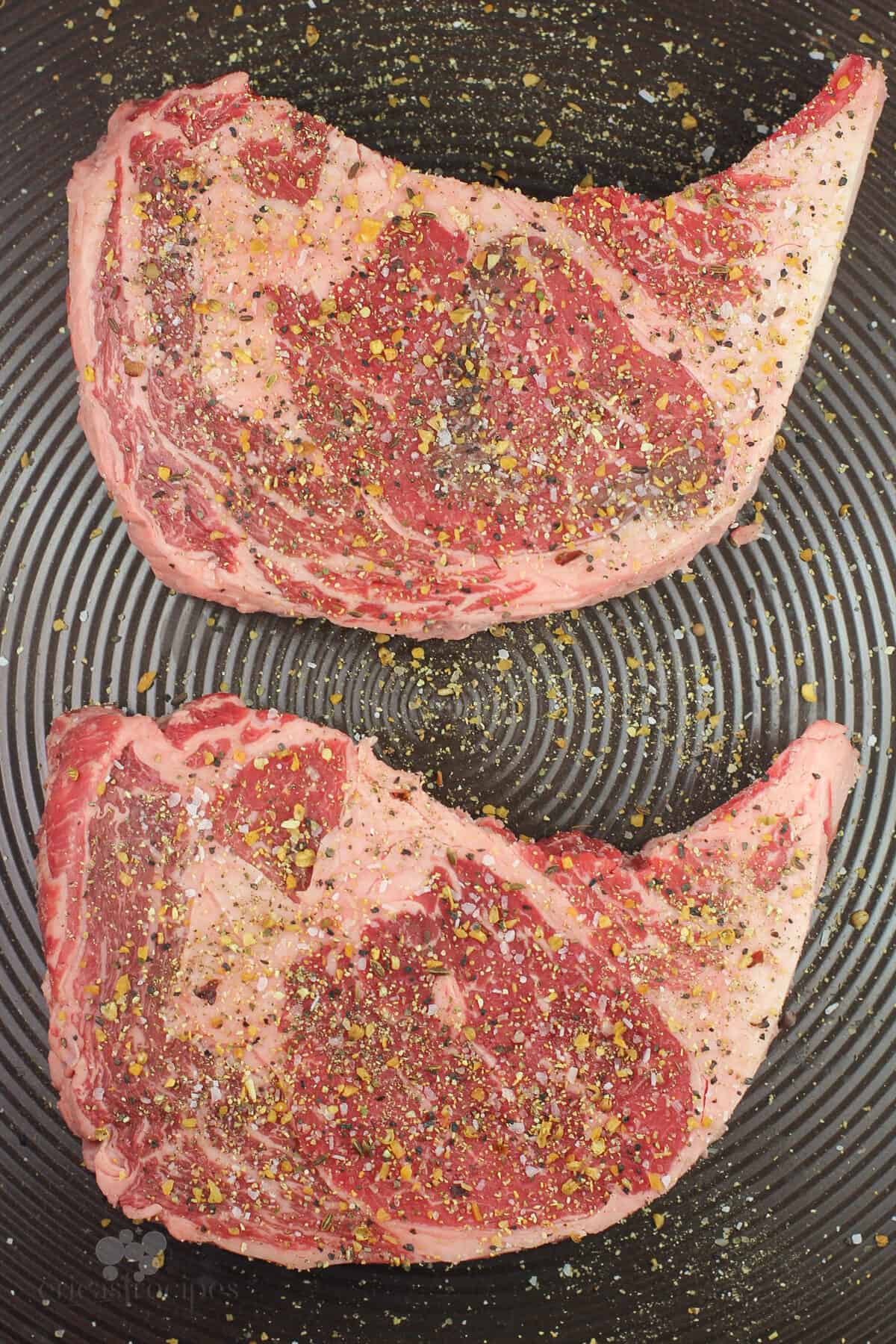 seasoned steaks on metal sheet before cooking