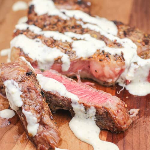 grilled steak on wood board topped with horseradish dijon sauce