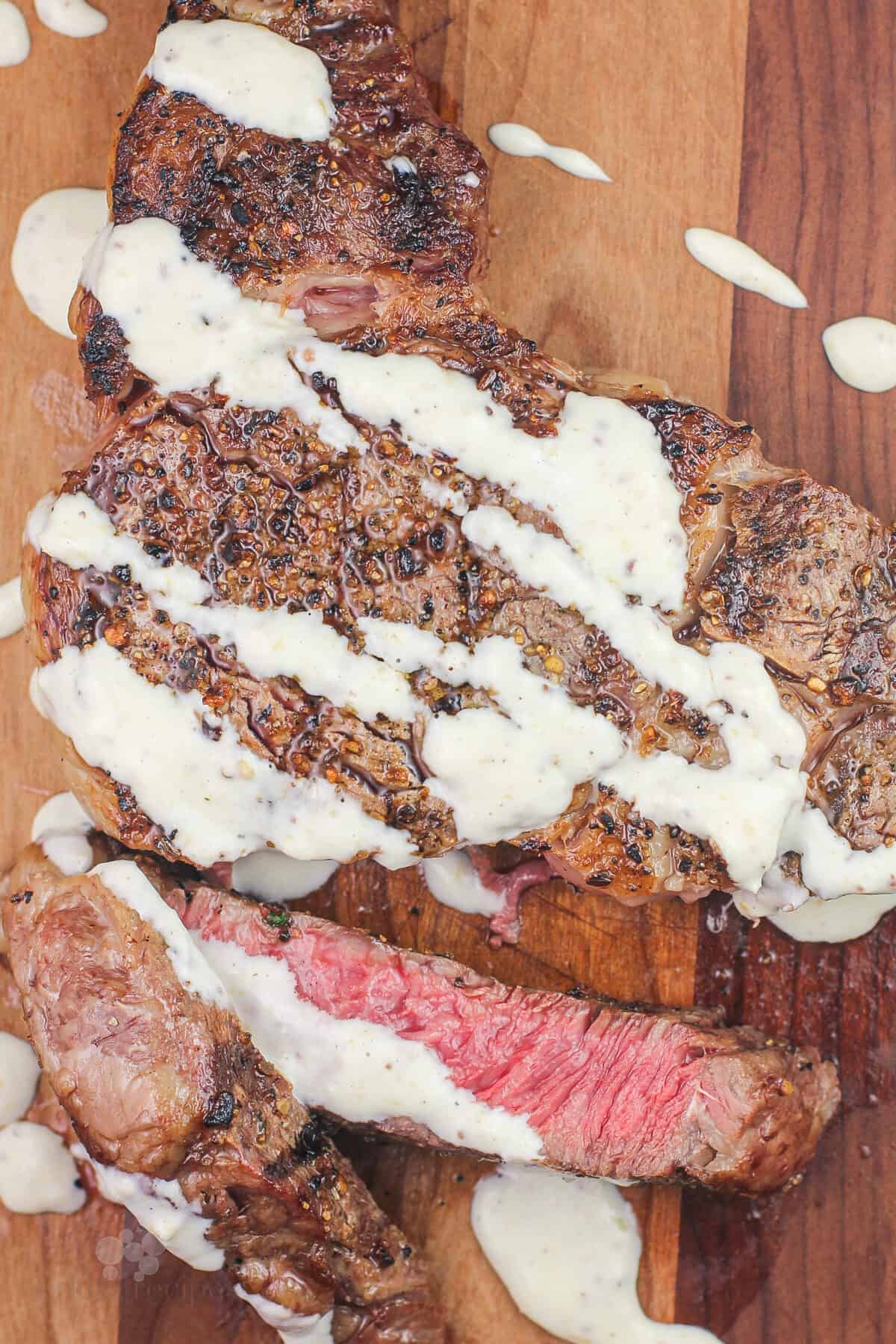 cut steak on wood board topped with horseradish dijon sauce