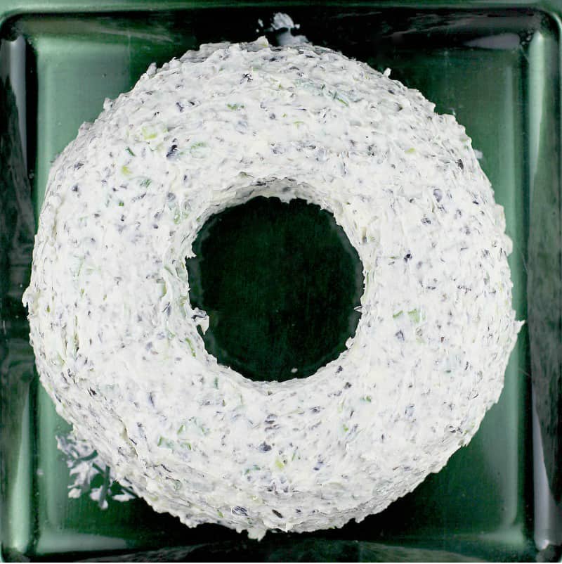 top down view of the formed christmas cheese wreath on a dark green plate, without garnish