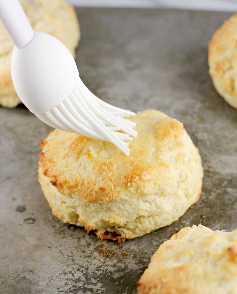 brush putting melted butter on a biscuit