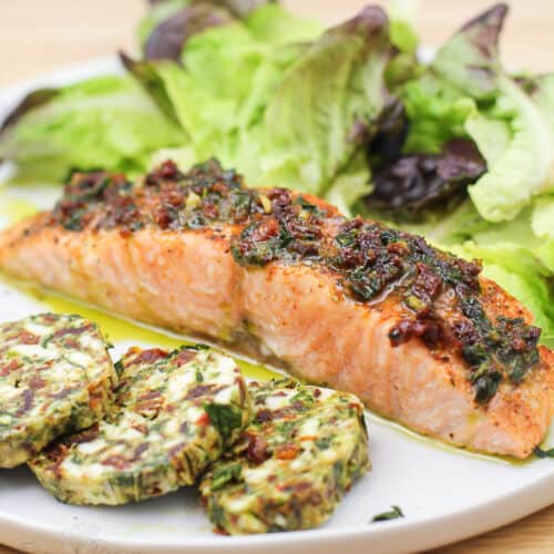 cooked salmon on white plate with salad and finishing butter