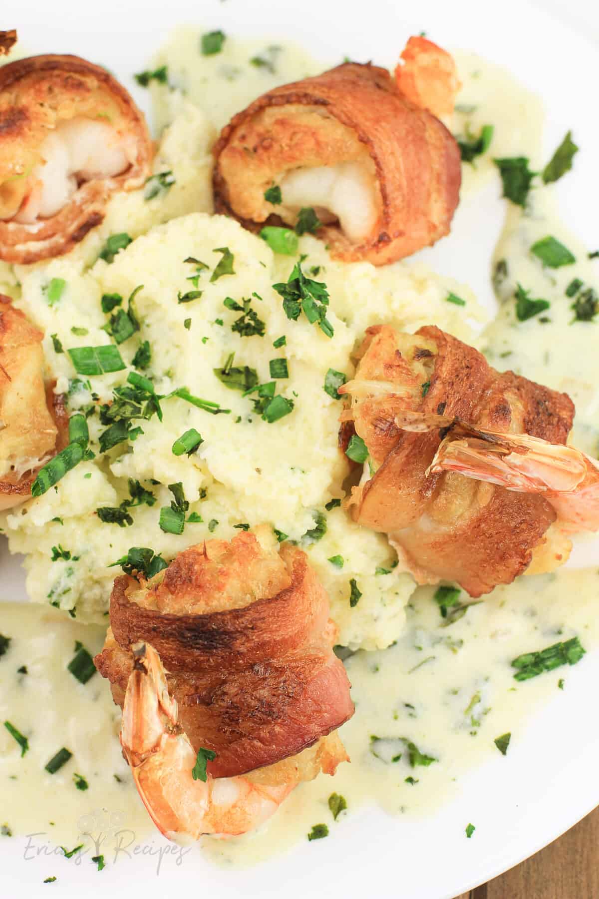 bacon wrapped shrimp on white plate with mashed potatoes