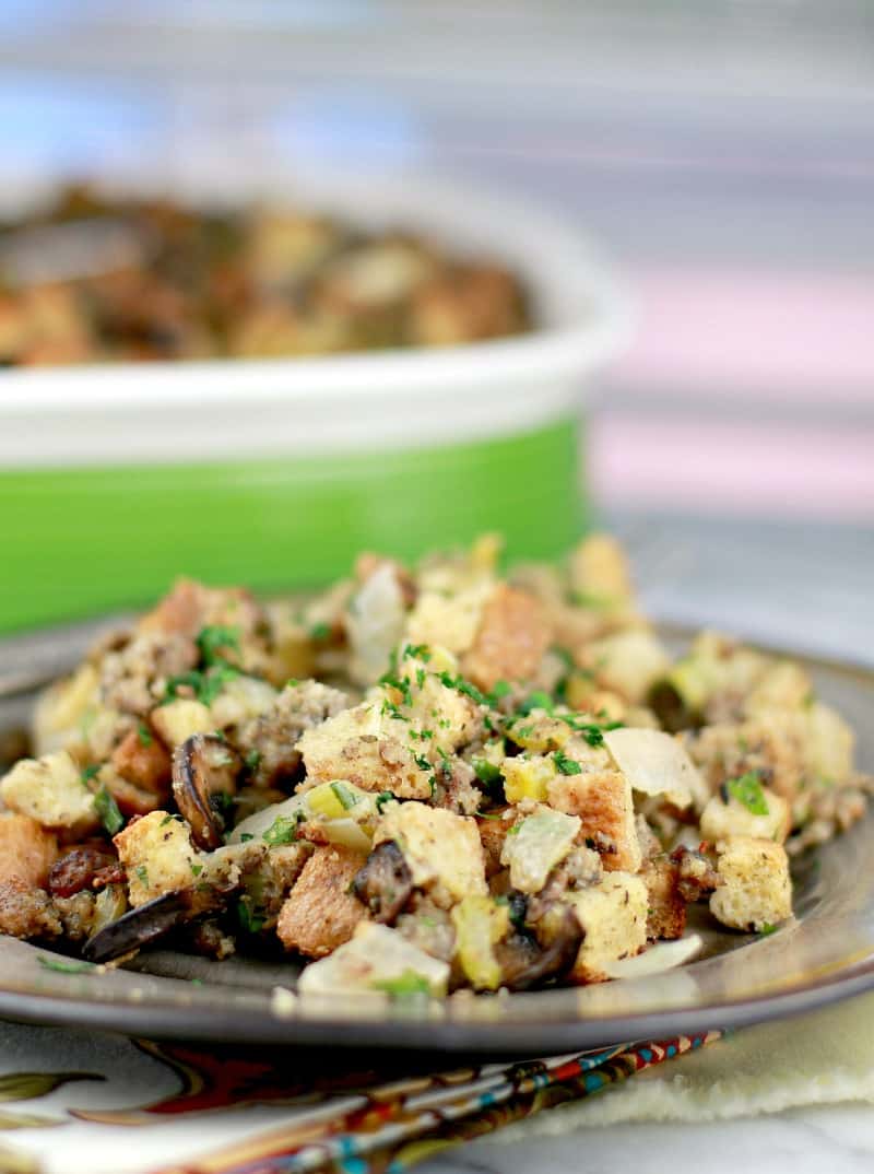 serving of stuffing plated on a brown ceramic plate ; casserole in the background