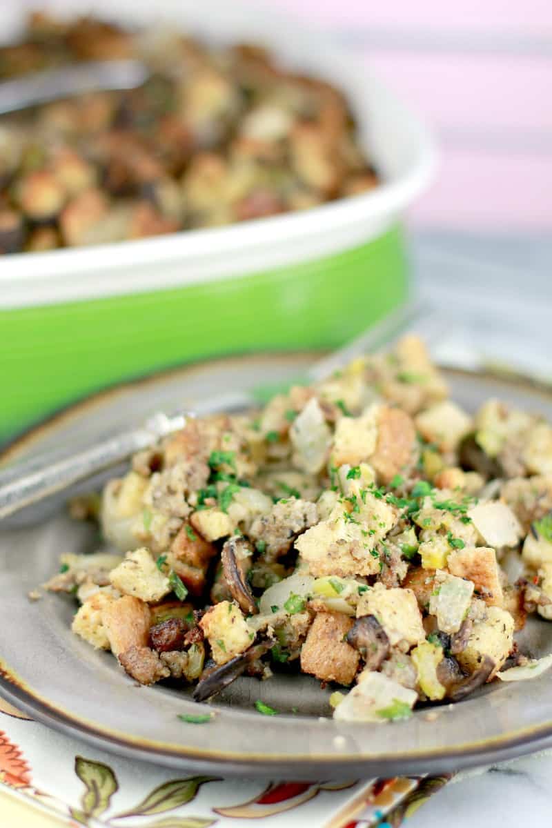 Finished presentation. Side view of stuffing plated on a brown ceramic plate; the rest of the stuffing casserole is in the background