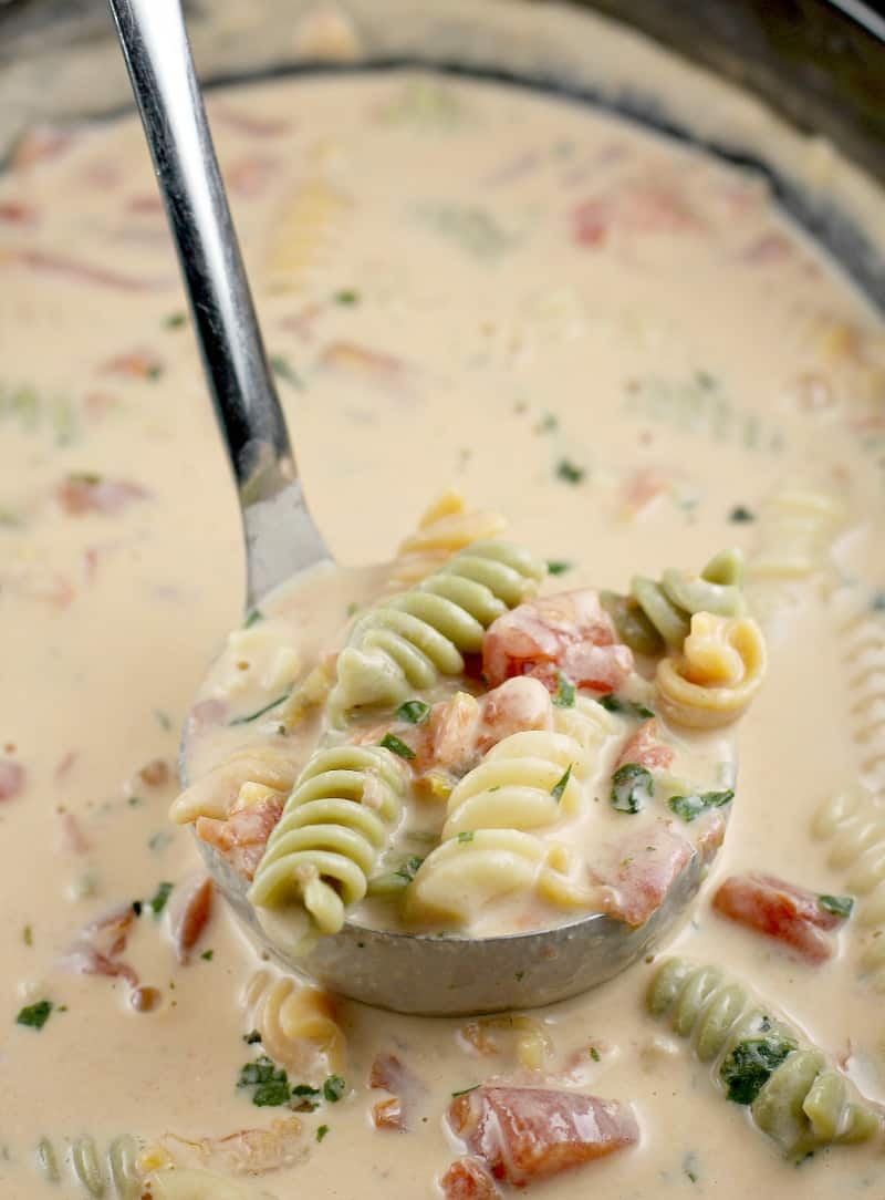 a ladle scooping up the tomato basil soup from the slow cooker