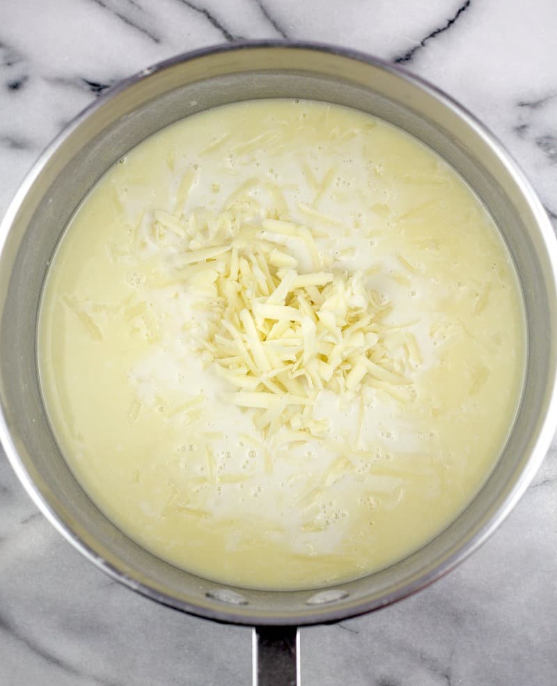 cheese added to white sauce in a pot to make the lemon cheese sauce