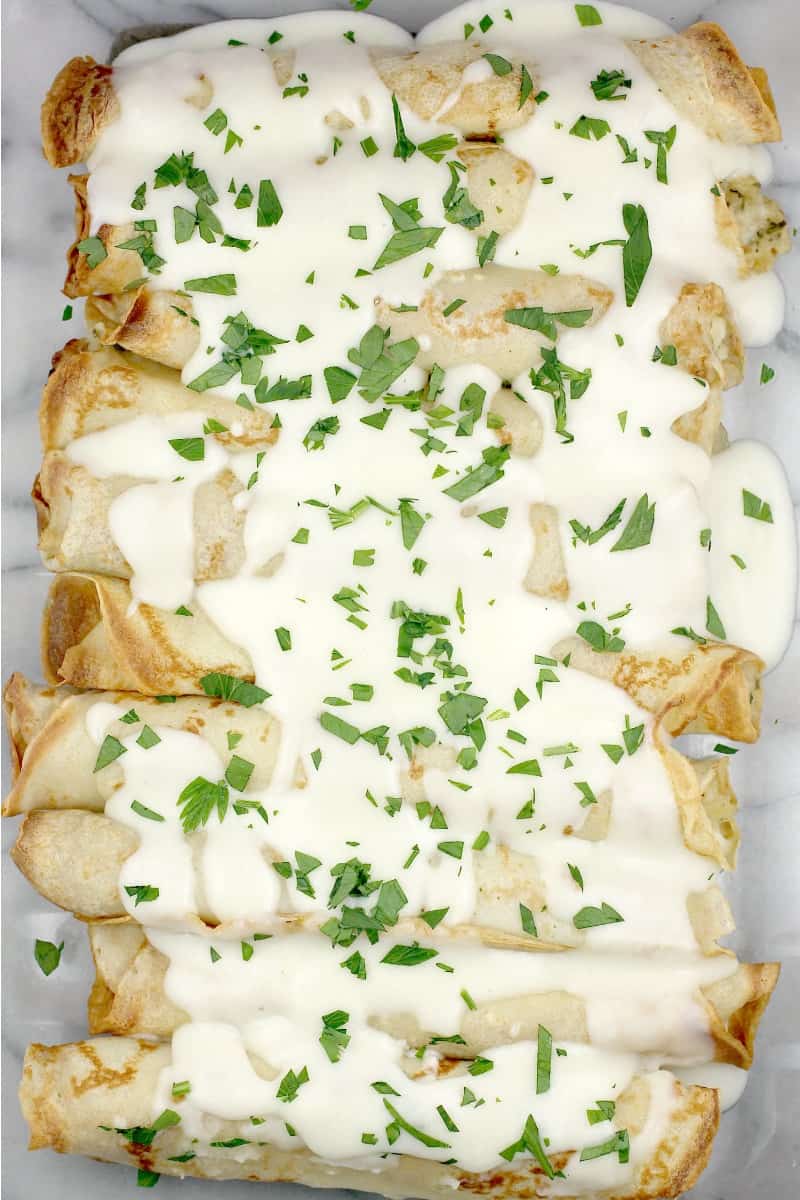 top down view into bake dish with finished crepes and lemon sauce spooned over