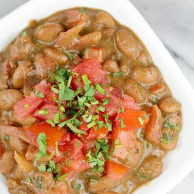 top view of finished frijoles charros beans in a small white dish on a marble surface