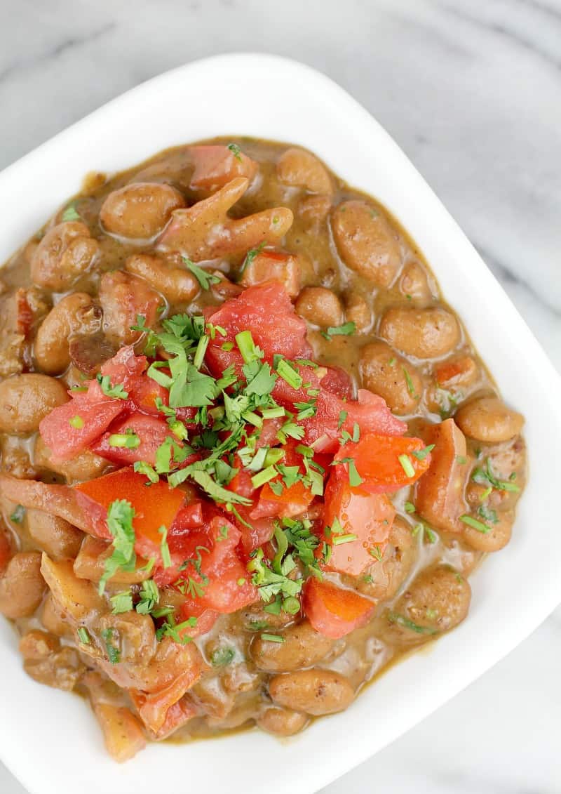 top view of finished frijoles charros beans in a small white dish on a marble surface