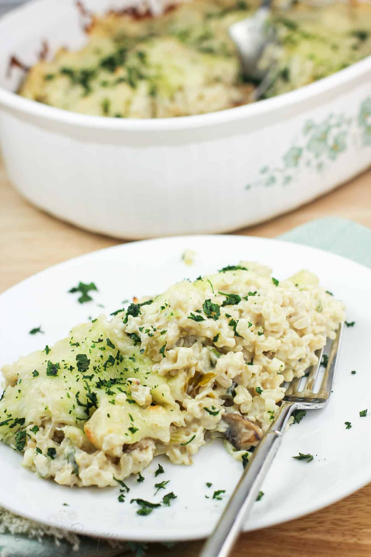 plated portion of green chile rice on white dish with fork; bake dish in the background