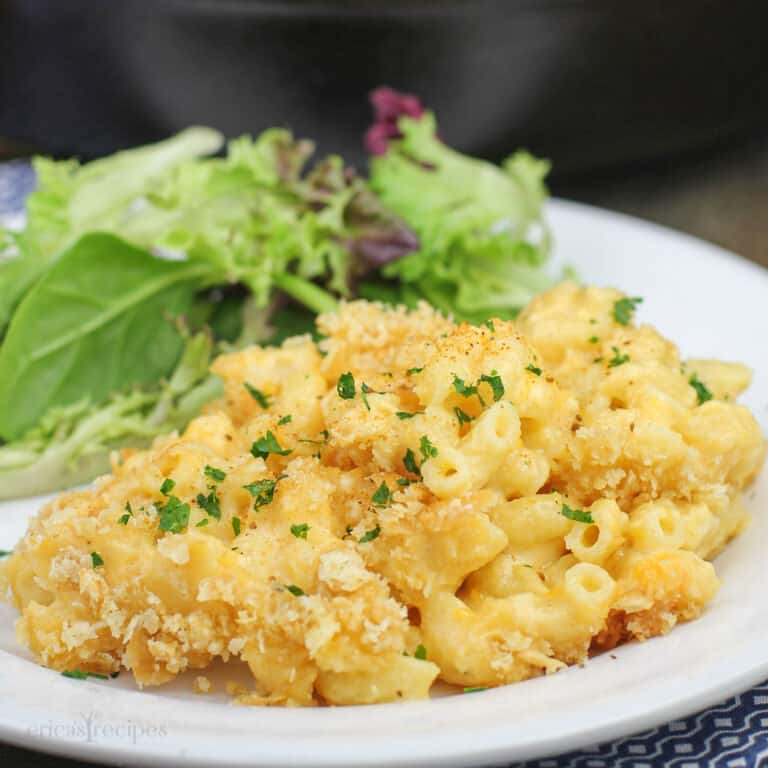 simple macaroni and cheese on white plate with salad; cast iron skillet in background