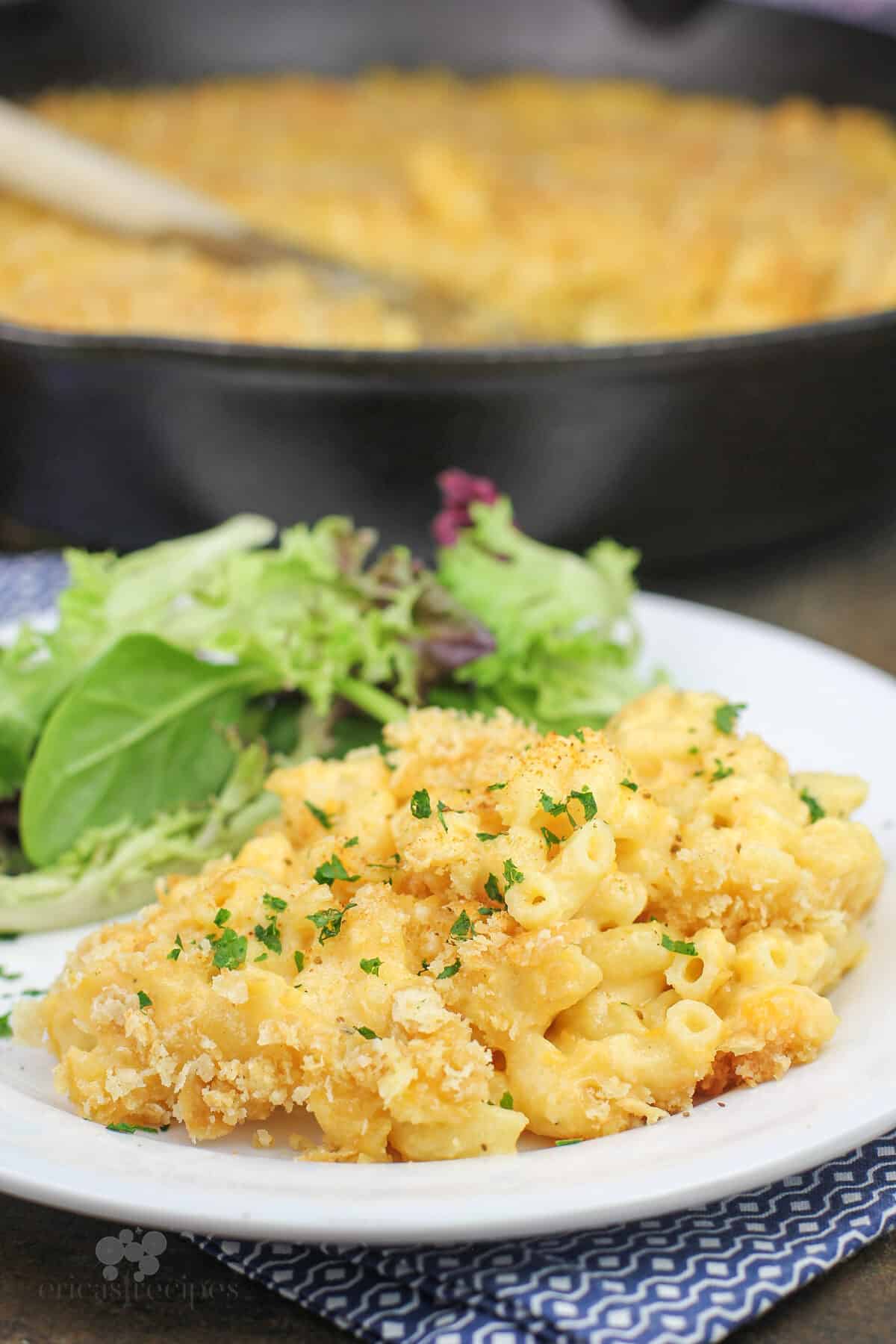 plated portion of macaroni and cheese, salad and skillet in background