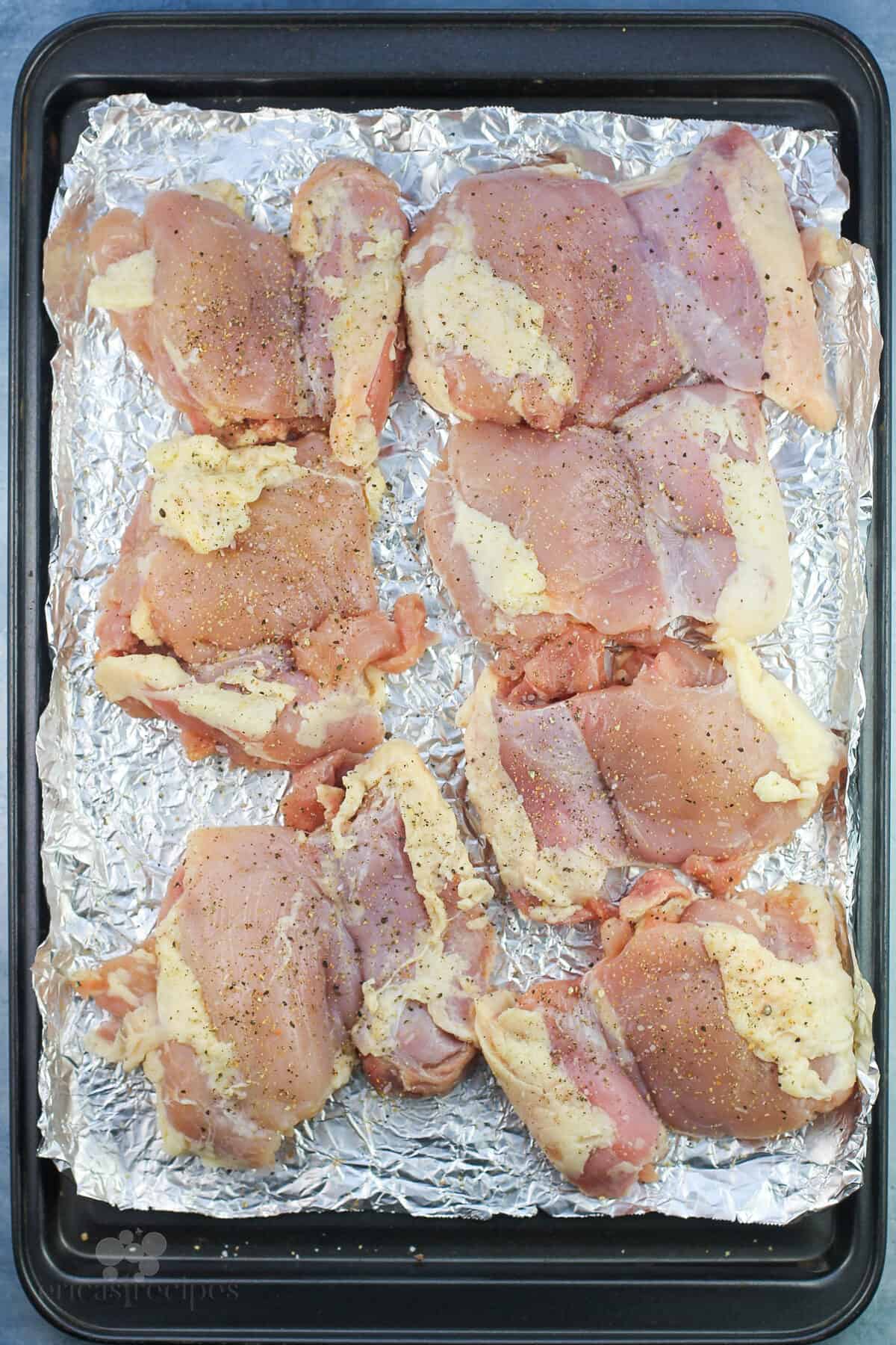 uncooked chicken thighs on bake sheet