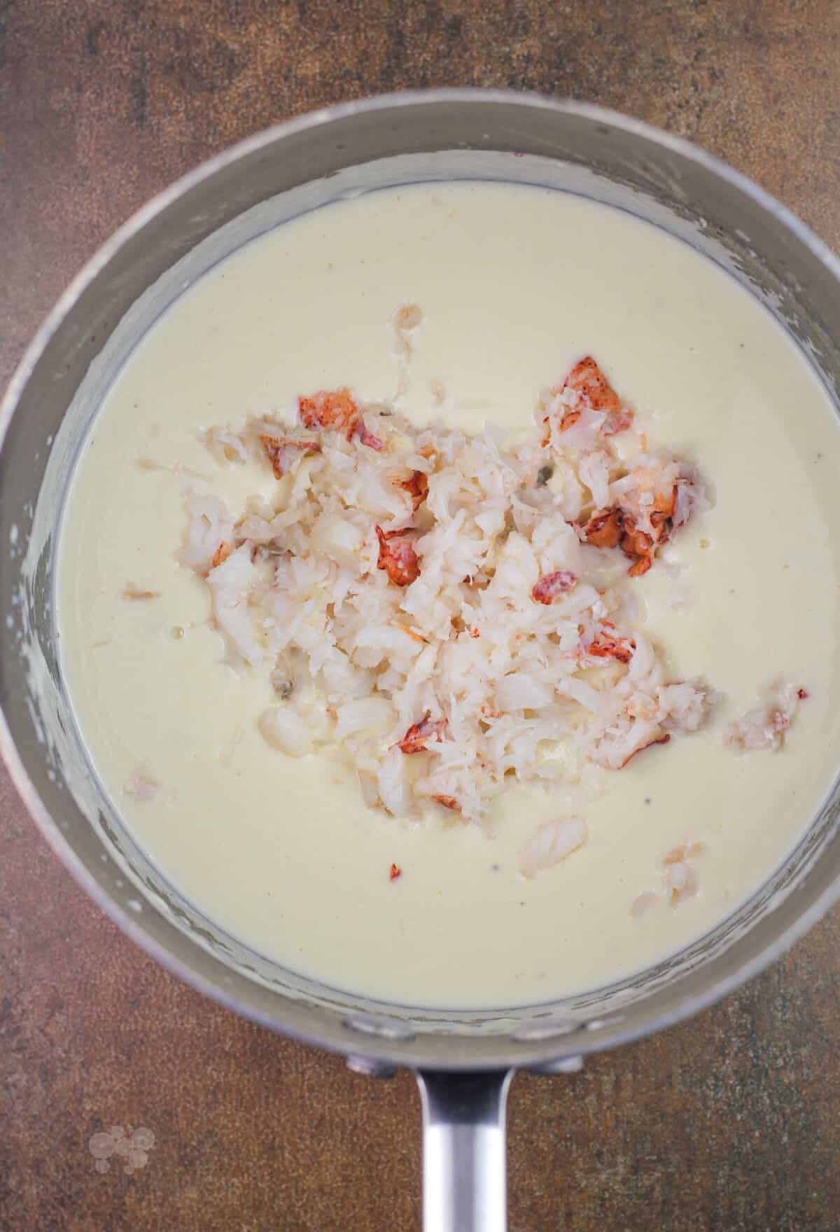 lobster in the center of white bechamel in saucepan