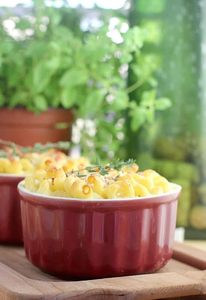 mac and cheese for two in two red ramekins on wood board