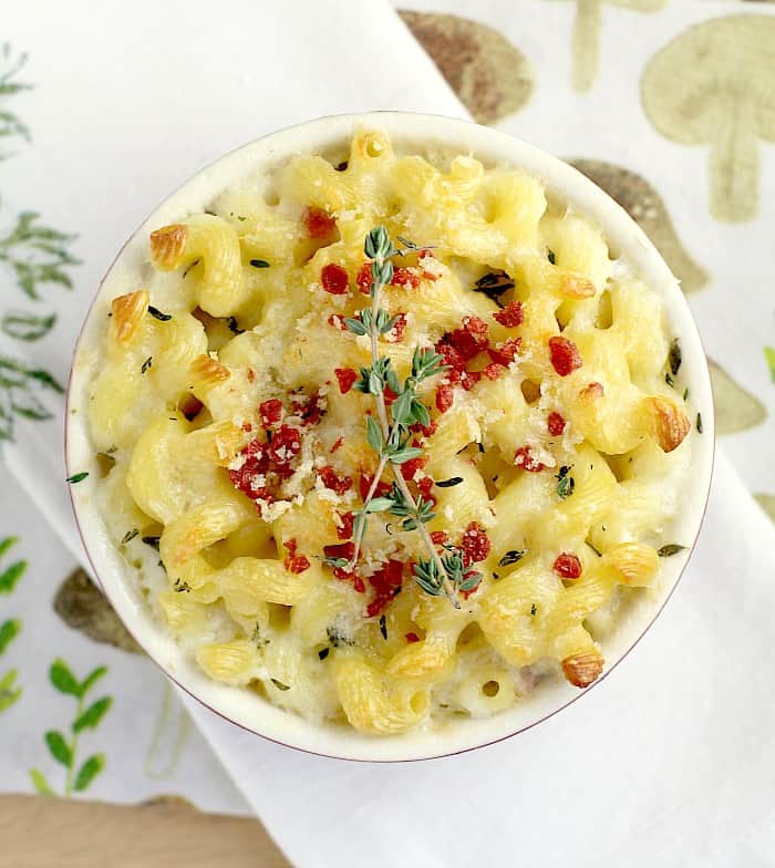 top down view of white wine mac and cheese in a small crock topped with bacon and thyme 