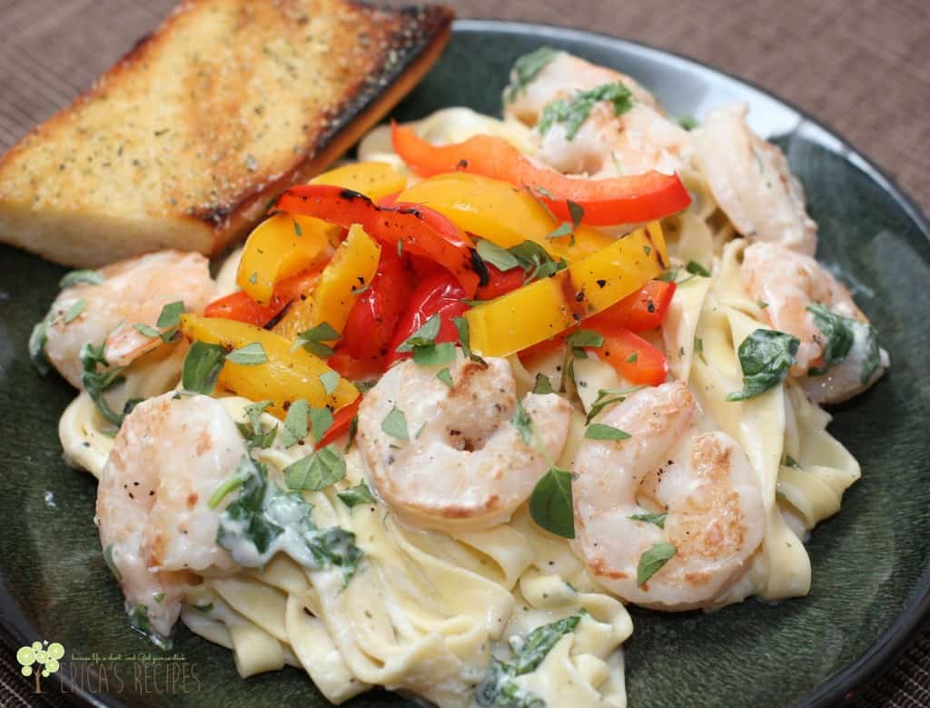 shrimp and pasta on green plate with peppers and boursin sauce; garlic bread is on the side