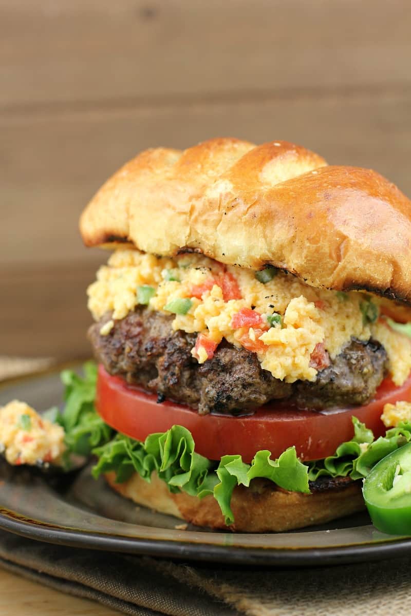 cheeseburger in a bun with lettuce, tomato, and pimento cheese