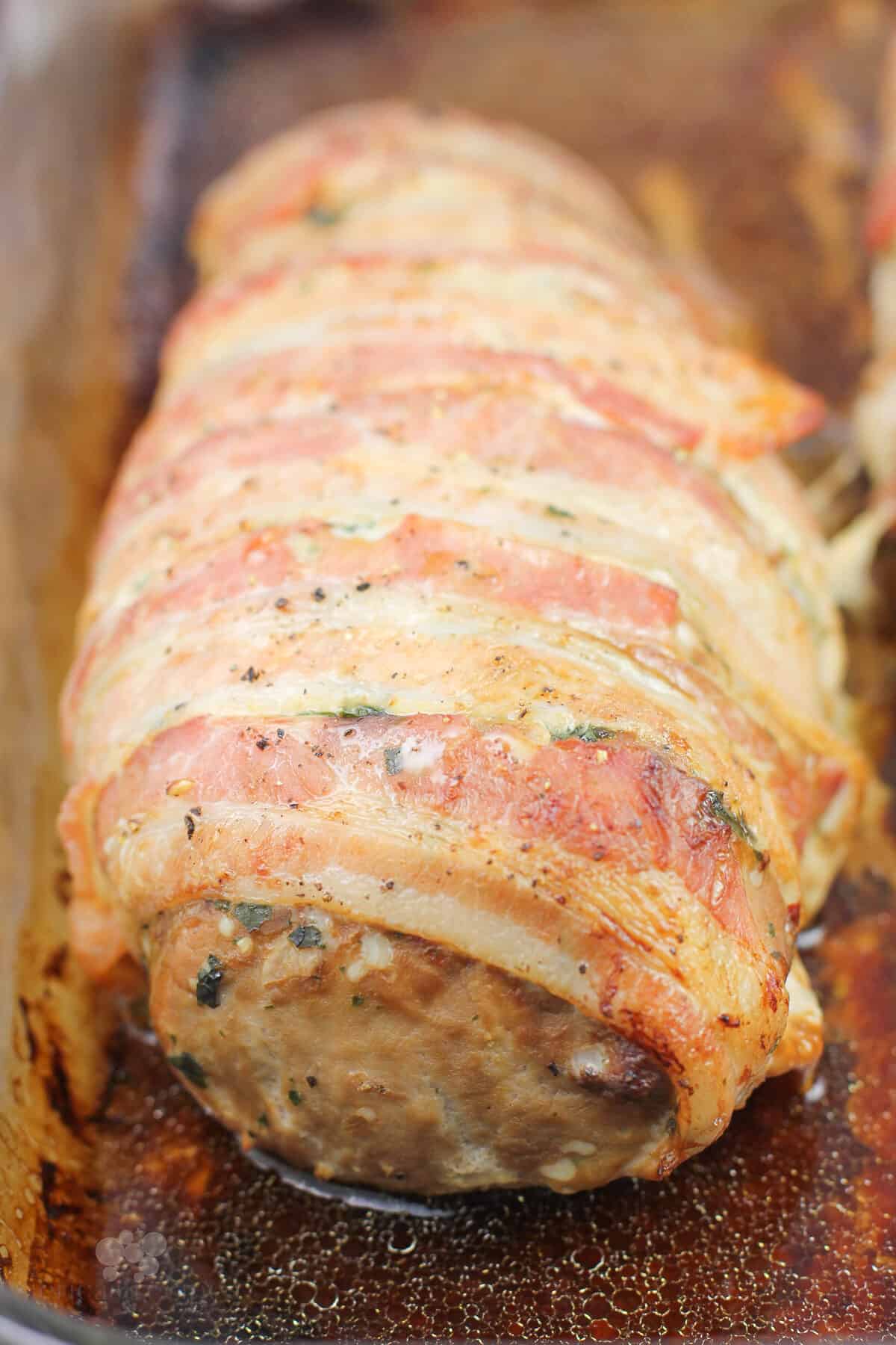 close view showing bacon wrapped around cooked pork