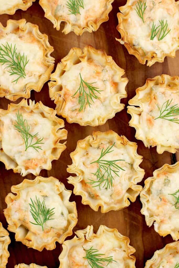 top down view a tray full of mini smoked salmon tarts with dill garnish