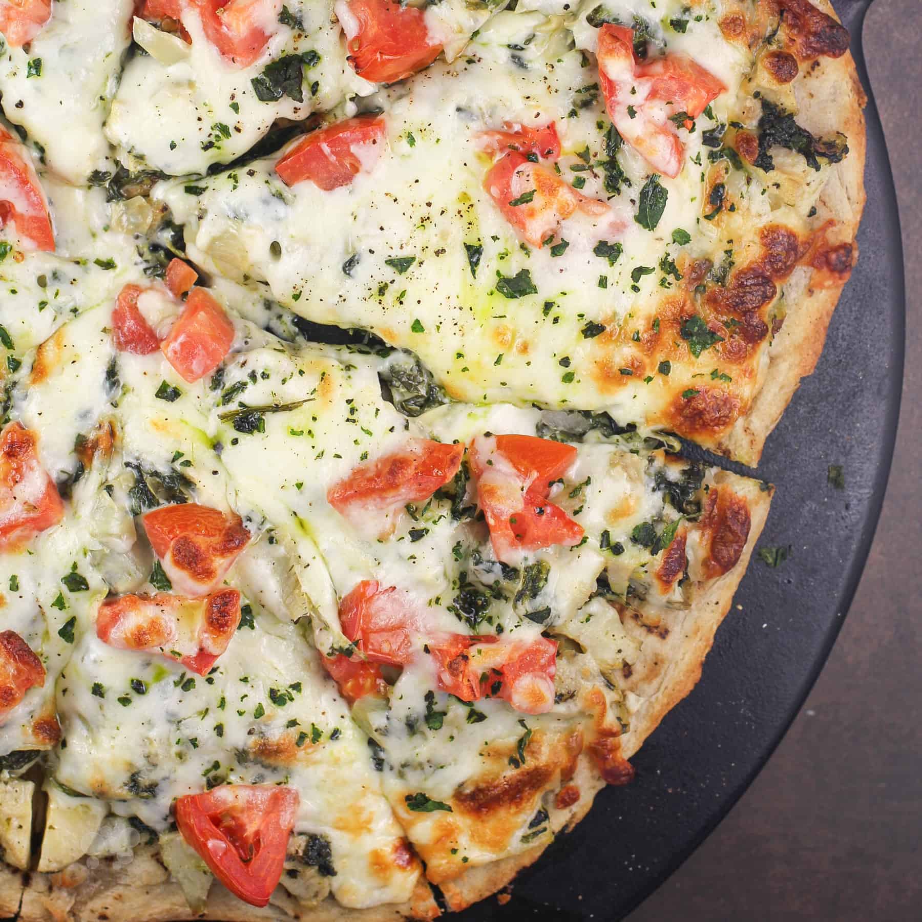 spinach artichoke pizza on pizza stone