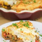 serving of prepared Mexican shepherd's pie on white plate; red pie plate in the background