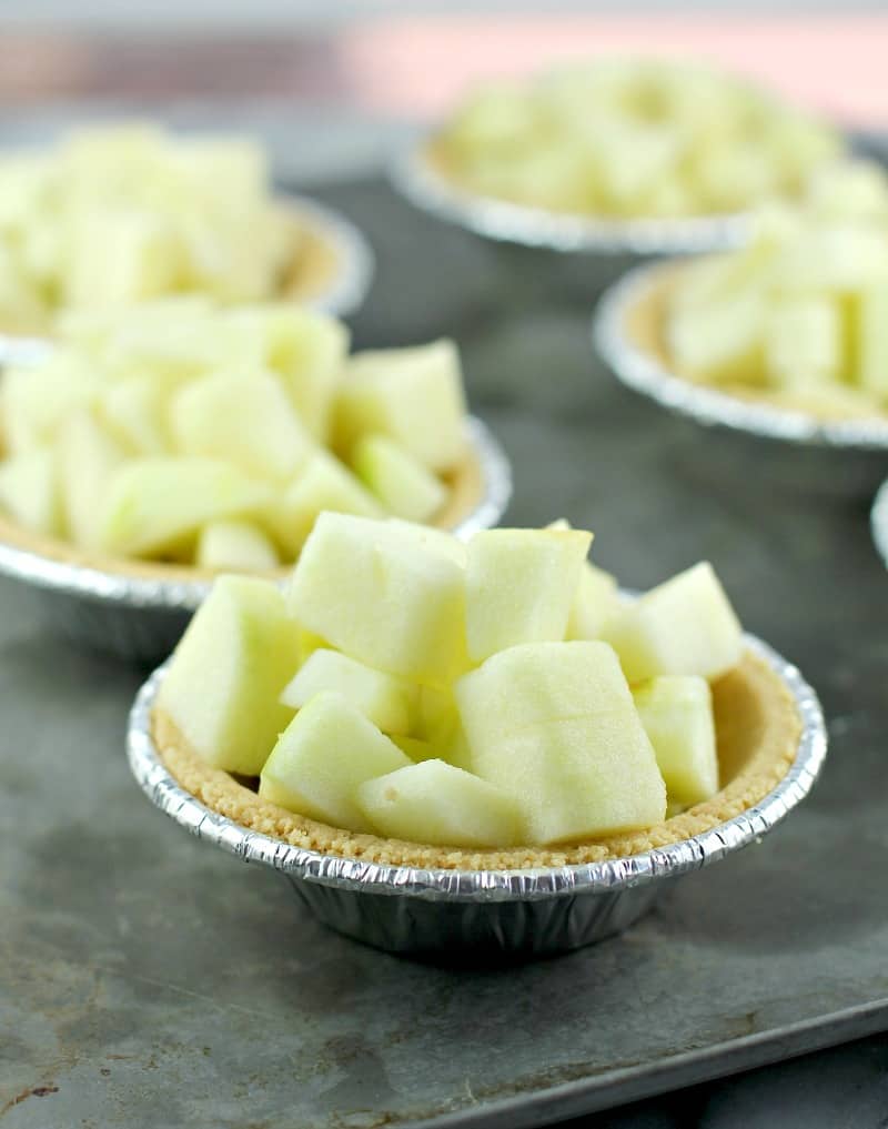 diced apple in a mini graham cracker tart shell on a metal sheet