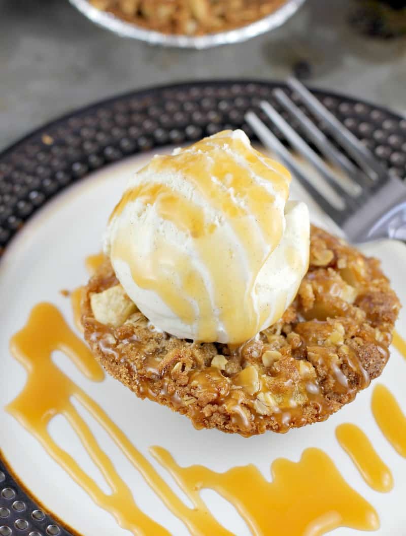 close view of mini apple crisp tart on a plate topped with ices cream and caramel