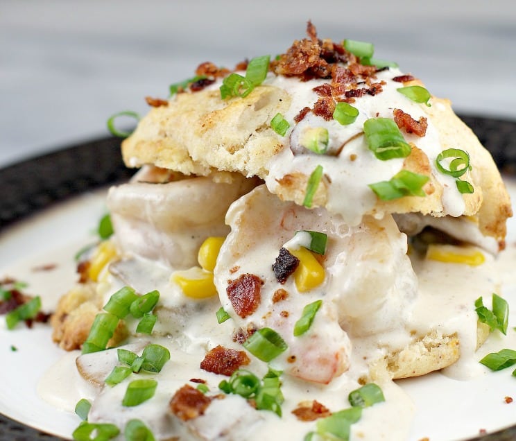 bacon biscuits filled with shrimp gravy on plate, topped with green onion