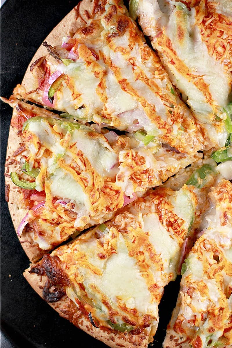 Top down view of this easy recipe with turkey; the finished pizza showing half of the sliced pizza on a black pizza stone.