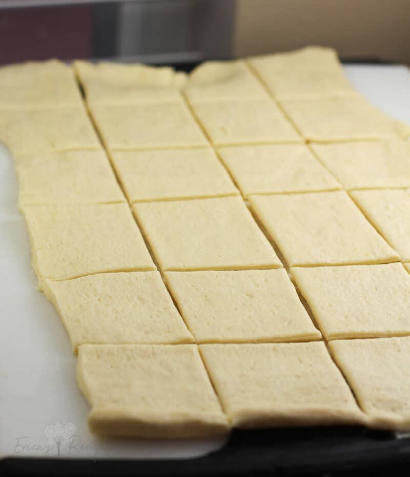 crescent dough sheet on white board cut into 24 squares