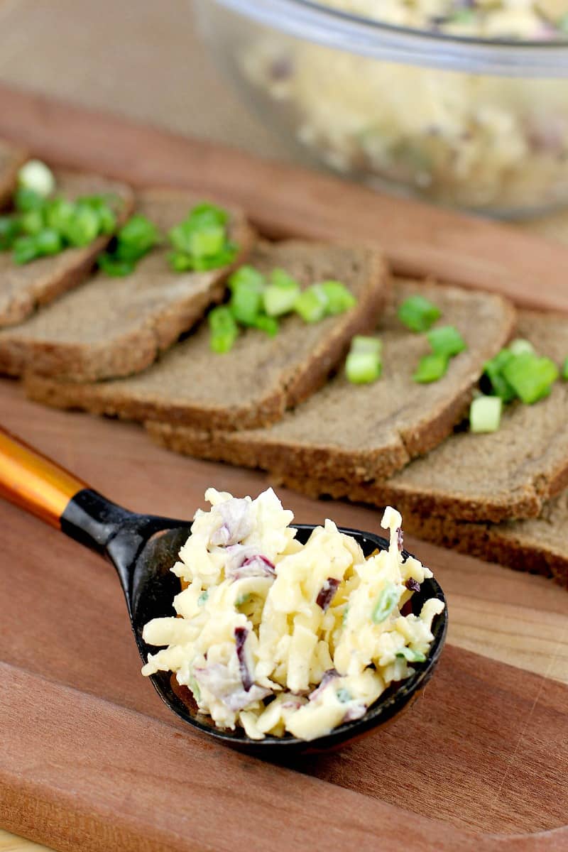 a Russian black and orange spoon holding a mound of this easy appetizer for a party; party bread is in the background