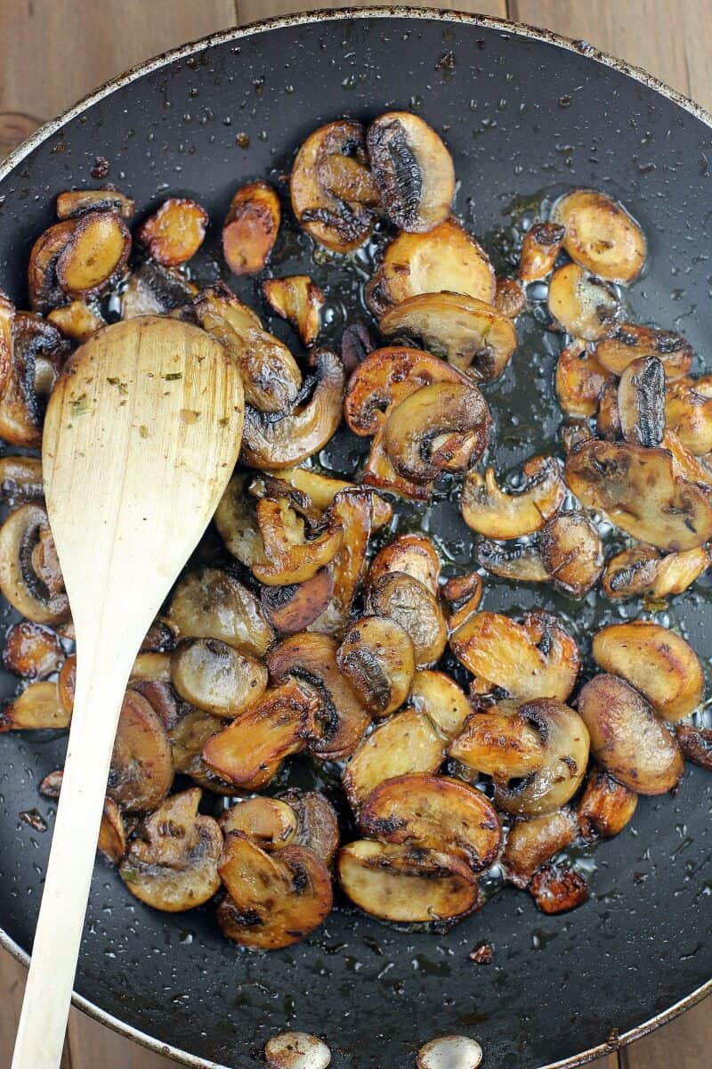 mushrooms in a skillet with wood spoon