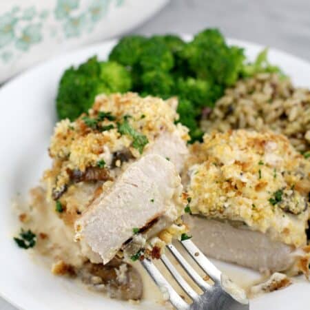 front view of finished pork, cut to show doneness plated on serving plate, rice and broccoli in the background