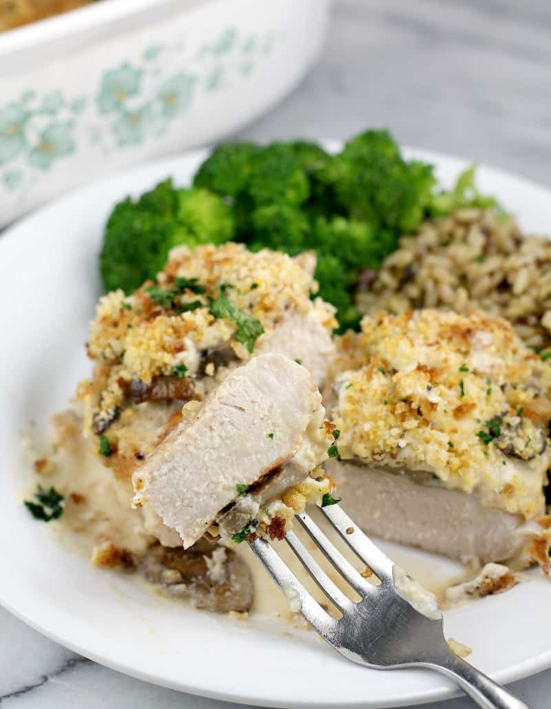 front view of finished pork, cut to show doneness plated on serving plate, rice and broccoli in the background