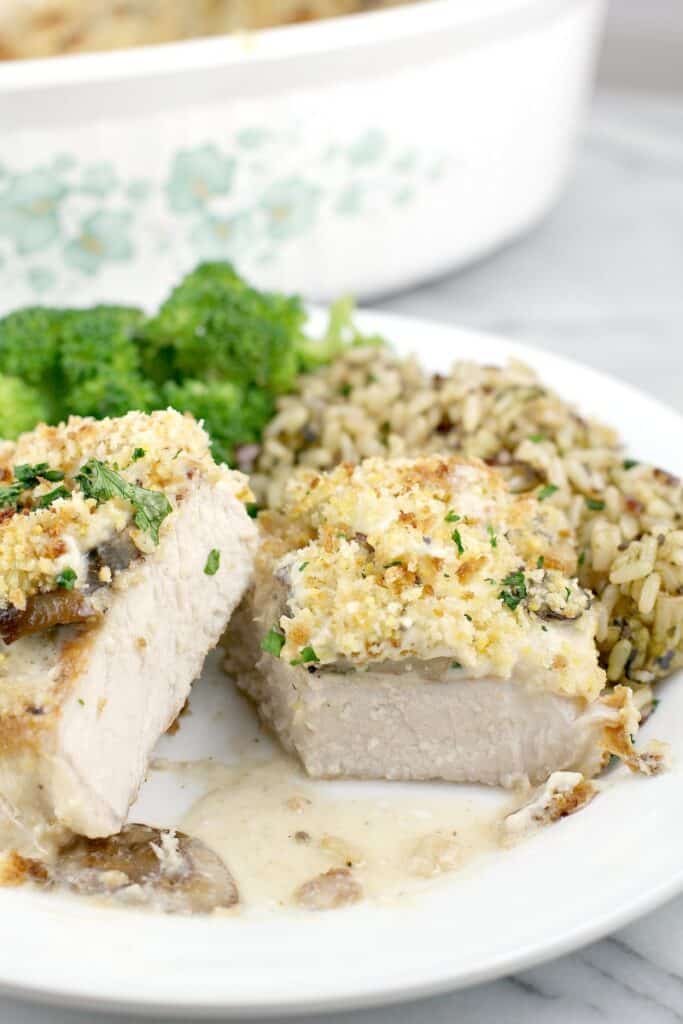 close front view of finished pork, cut to show doneness plated on serving plate, rice and broccoli in the background