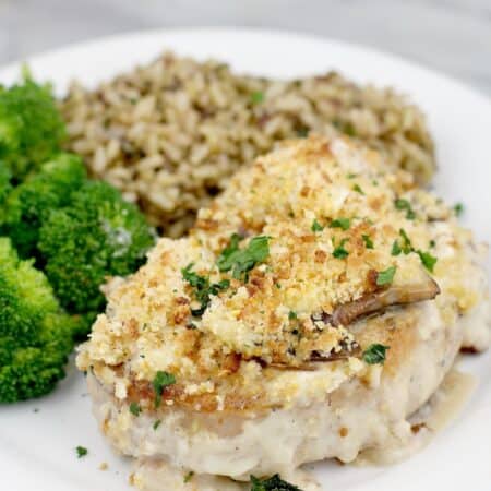 front view of finished pork plated on serving plate, rice and broccoli in the background