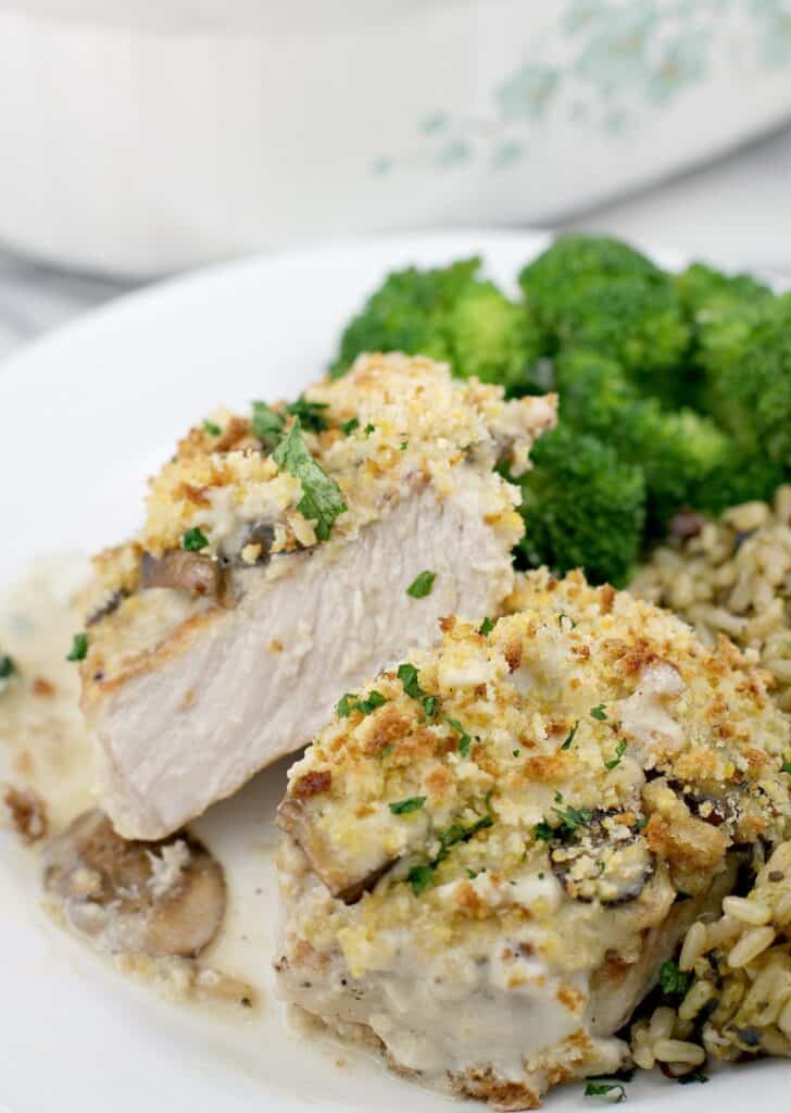 front view of finished pork, cut to show doneness plated on serving plate, rice and broccoli in the background