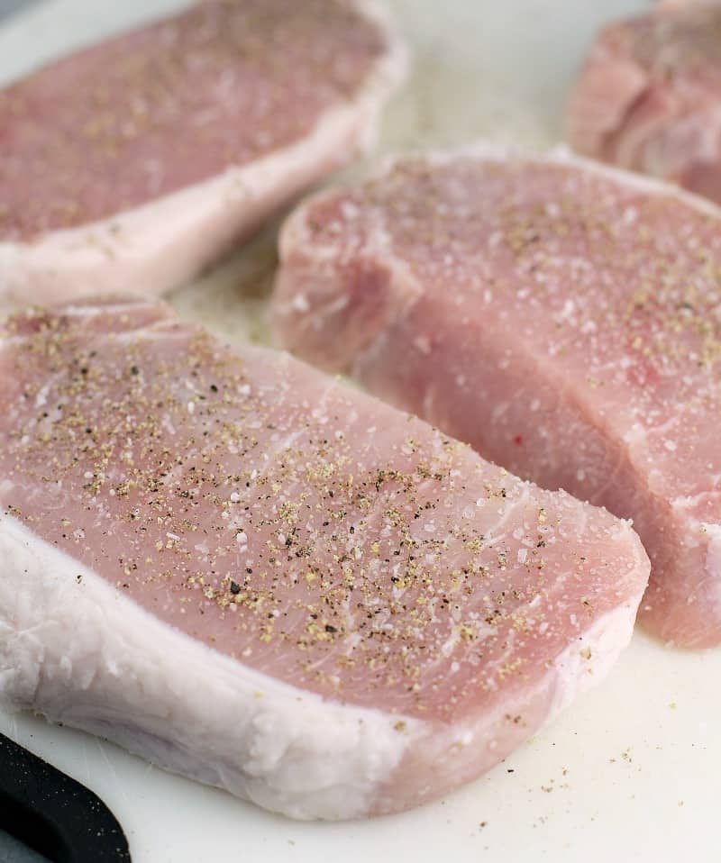 uncooked boneless loin pork on a white cutting board to show seasoning