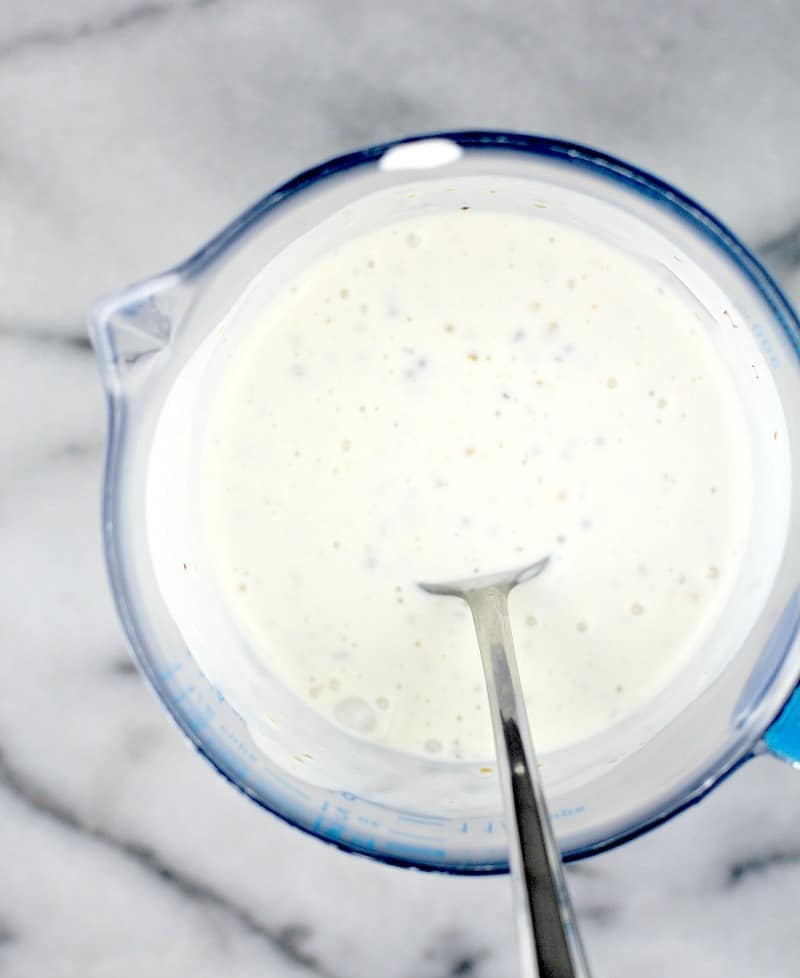 the mustard and cream mixed in a glass measuring cup with a spoon