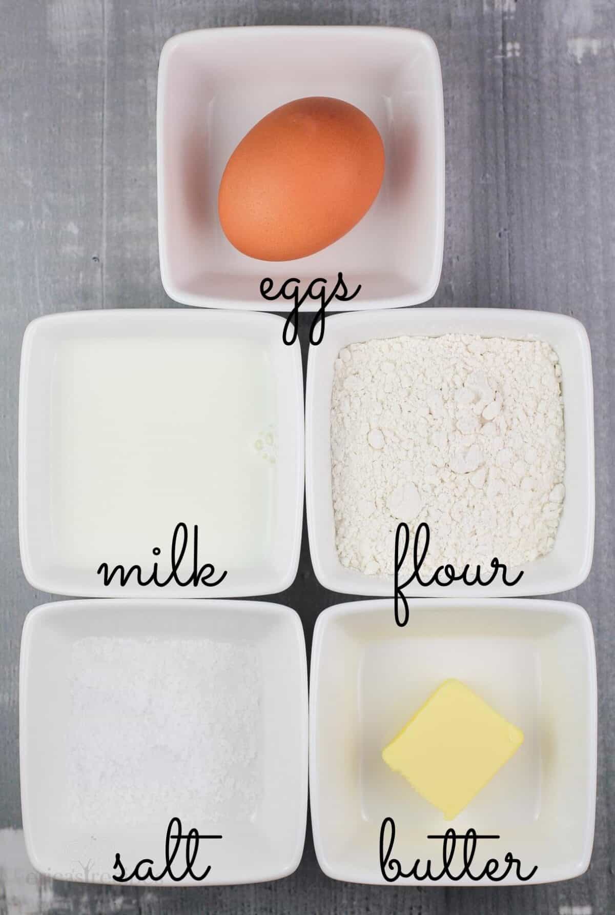 5 small white bowls with ingredients labeled eggs, milk, flour, salt, butter